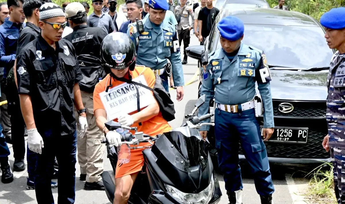 Image Credit Tumpal Andani Aritonang/Beritasatu - Penyidik Detasemen Polisi Militer Pangkalan TNI Angkatan Laut (Denpomal) Banjarmasin menghadirkan tersangka pembunuhan jurnalis, oknum TNI AL Kelasi Satu Jumran (baju oranye) mengatur posisi motor korban setelah menghabisi nyawa korban di dalam mobil dalam rekonstruksi 33 adegan di Tempat Kejadian Perkara (TKP), Jalan Trans Gunung Kupang, Kelurahan Cempaka, Kecamatan Cempaka, Kota Banjarbaru, Kalimantan Selatan, Sabtu (5/4/2025).