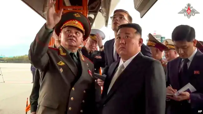 Image Credit Via AP - Pemimpin Korea Utara Kim Jong Un mendengarkan Menteri Pertahanan Rusia Sergei Shoigu saat memeriksa pesawat tempur Rusia di Vladivostok, Rusia, 16 September 2023.