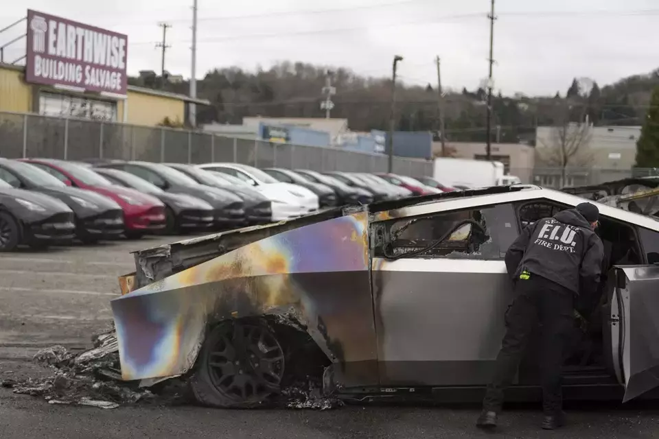 Image Credit AP - Seorang anggota Departemen Pemadam Kebakaran Seattle memeriksa Tesla Cybertruck yang terbakar di Seattle, Senin 10 Maret 2025.
