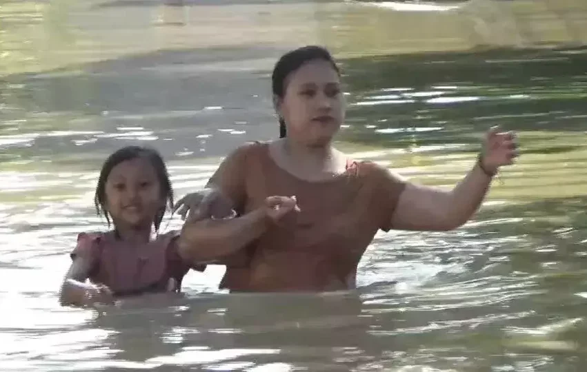 Seorang ibu dan anak menembus banjir di Desa Ploso, Kecamatan Karangtengah, Kabupaten Demak, Jawa Tengah, Minggu 18 Mei 2025. (Beritasatu/Jamaah)