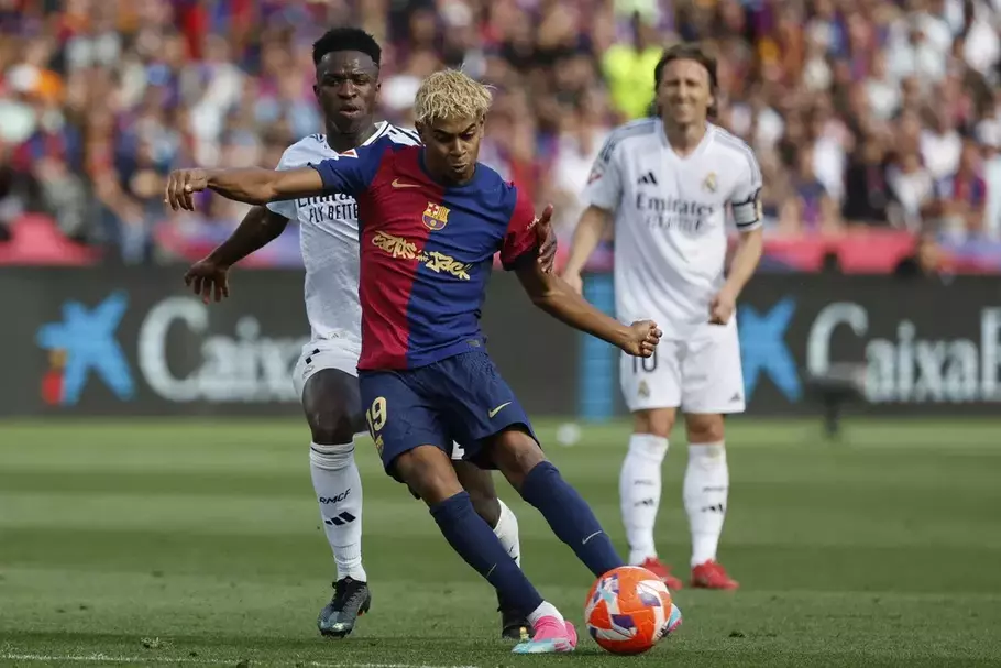 Penyreng Barcelona Lamine Yamal melepaskan tendangan di depan pemain Real Madrid Vinicius Junior dalam partai Luga Spanyol di Stadion Lluis Company, Minggu, 11 Mei 2025. - (AP/Joan Monfort)
