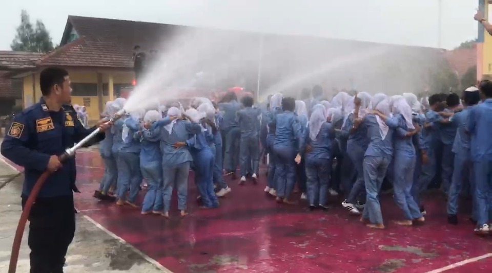 Ratusan siswa kelas 12 SMK Negeri 1 Tambelang, Kabupaten Bekasi, merayakan kelulusan dengan bermandikan air dari mobil pemadam kebakaran, Sabtu, 3 Mei 2025. (Beritasatu/Eka Jaya Saputra)