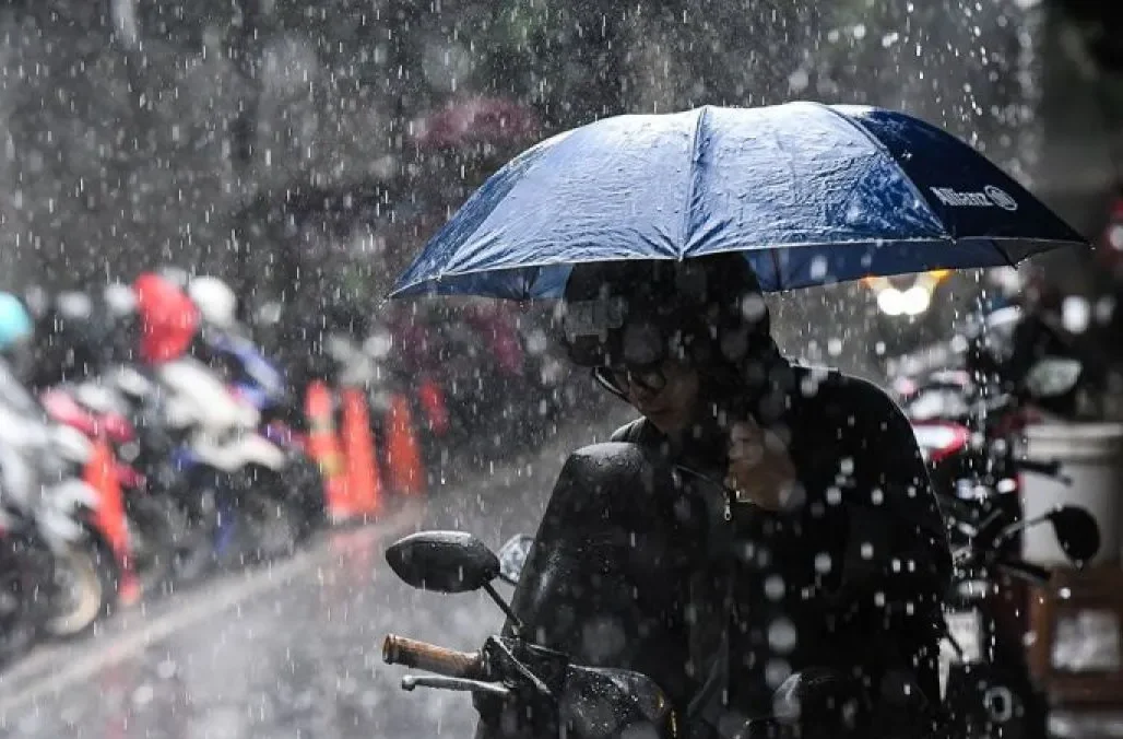 Pengendara sepeda motor menggunakan payung saat hujan di kawasan Senopati, Jakarta, Jumat (14/3/2025). (Antara/Sulthony Hasanuddin)